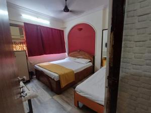 ムンバイにあるSai residencyの小さなベッドルーム(ベッド2台、赤いカーテン付)