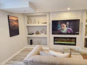 a living room with a couch and a tv on a wall at Stylish Retreat in North Oshawa in Oshawa