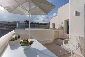 a balcony with a bowl of fruit and an umbrella at Lithos Houses in Pyrgos