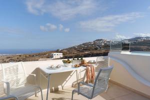 a table and chairs on a balcony with a view of the ocean at Lithos Houses in Pyrgos
