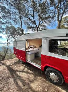 une camionnette rouge et blanche garée dans un champ dans l'établissement Van Camper Ibiza MB100 Van Voyage, à Sant Carles de Peralta