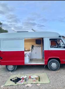 une camionnette rouge et blanche avec sa porte ouverte dans l'établissement Van Camper Ibiza MB100 Van Voyage, à Sant Carles de Peralta
