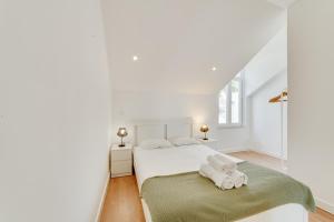 a white bedroom with a bed with towels on it at By the Palace - Ajuda Apartments in Lisbon