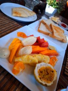 a white plate with fruit and vegetables on a table at Thara Cabana in Bentota