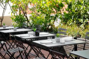 a group of tables and chairs with plates and plants at The Modernist Thessaloniki in Thessaloniki