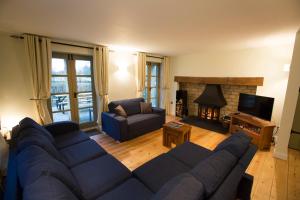 un salon avec un canapé bleu et une cheminée dans l'établissement Pet friendly Cotswold Cottage with hot tub and swimming pools, à Somerford Keynes