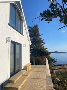 a house with a wooden walkway next to the water at Urgha Bay in Tarbert