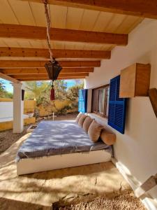 una camera da letto con un letto con persiane blu e un soffitto di Casa Migjorn, immersa nella natura a pochi passi dal mare a Es Caló de Sant Agustí