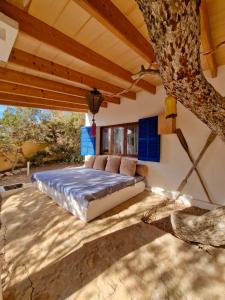 un letto nel mezzo di una stanza con un albero di Casa Migjorn, immersa nella natura a pochi passi dal mare a Es Caló de Sant Agustí