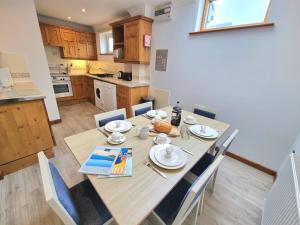 cocina y comedor con mesa de madera y sillas en Tregurrian Villas, en Newquay