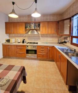 a large kitchen with wooden cabinets and a sink at Casa Migjorn, immersa nella natura a pochi passi dal mare in Es Calo