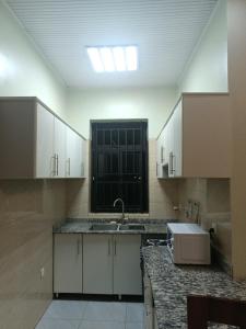 吉佳利的住宿－MANOVA BOUTIQUE HOTEL KIGALI，厨房配有白色橱柜、水槽和窗户。
