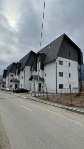 a large white building with black roofs on a street at Busteni Mountain View Suites by the River - EV Plug in Buşteni