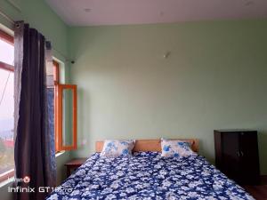 um quarto com uma cama com um cobertor azul e branco em Sunrise Home Stay em Almora