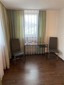 リングスハイムにあるGasthaus zum Hirschenの椅子2脚、ガラステーブル、窓が備わる客室です。