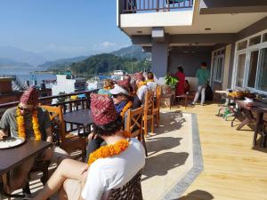 a group of people sitting on a balcony with hats on at Beli Guest House in Pokhara