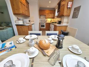 a kitchen with a wooden table with white dishes on it at Tregurrian Villas in Newquay