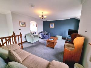 a living room with a couch and chairs and a tv at Tregurrian Villas in Newquay