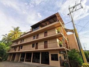 un grand bâtiment avec un balcon et des palmiers dans l'établissement Pacific Inn hotel, à Sayulita