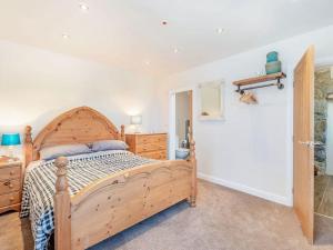 a bedroom with a wooden bed and a bathroom at Pipistrelle Cottage a quirky gem near Snowdonia in Caernarfon