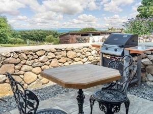 a table and chairs with a stove and a stone wall at Pipistrelle Cottage a quirky gem near Snowdonia in Caernarfon