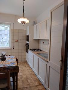 a kitchen with white cabinets and a table and a window at Appartamento con posto auto privato comodo a centro e spiagge in Lavagna