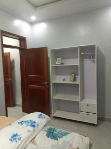 キガリにあるMANOVA BOUTIQUE HOTEL KIGALIのベッドの横に白い本棚が備わるベッドルーム