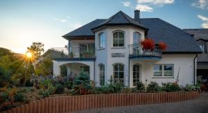 a white house with flowers on the balcony at Hotel Bisenius in Traben-Trarbach