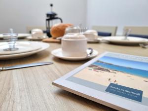 a tablet on a wooden table with a cup and plates at Tregurrian Villas in Newquay