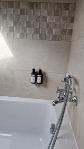 two bottles ofodorizers sitting on a shelf above a bath tub at Hotel Dandy Rouen centre in Rouen