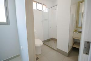 Baño blanco con aseo y lavamanos en Lagos Apartaestudios Apartamento, en Barranquilla