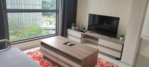 uma sala de estar com uma televisão de ecrã plano e uma janela grande em The Robertson Bukit Bintang by Wowhome em Kuala Lumpur