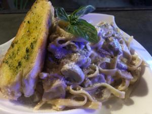 een bord pasta met een broodje en een pakje basilicum bij Bucana Beach Camp in El Nido