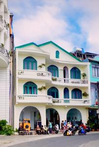 ein großes weißes Gebäude mit Menschen, die davor sitzen in der Unterkunft Tường Vy Dalat Central in Da Lat