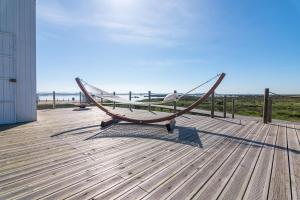 a wooden bench on a deck with the beach at Tijosa Eco-House Camp in Ovar