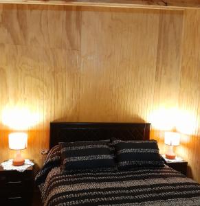 a bedroom with a bed with two lamps on tables at Cabaña Cacique Vista Hermosa in Cochamó