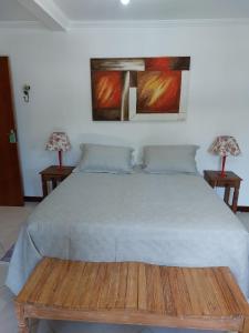 a bed in a bedroom with two lamps on tables at Pousada Banzay in Paraty