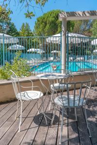 einen Tisch und Stühle auf einer Terrasse neben einem Pool in der Unterkunft Le Mas de La Crémaillère in Gréoux-les-Bains