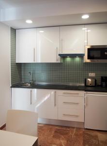 eine Küche mit weißen Schränken und einem Waschbecken in der Unterkunft Apartamentos Embalse de Orellana in Orellana la Vieja
