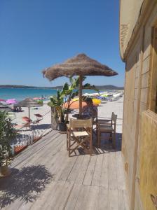 a person sitting at a table under an umbrella on the beach at tommy house in Calasetta