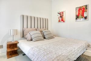 a white bedroom with a bed with two pillows at Modern victorian city house, work, live, play! in Cape Town