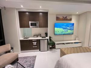 una camera con letto e una cucina con TV di NEW Luxury Hotel Suite Sandton City a Johannesburg