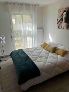 a bedroom with a large white bed and a window at T2 Cosy avec jardin Barcares Village in Le Barcarès