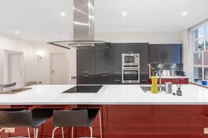 une cuisine avec un comptoir blanc et des appareils noirs dans l'établissement Casa Italia near Kensington High Street - Wifi & Washing Machine, à Londres