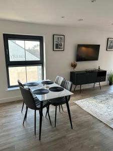 a dining room with a table and chairs and a television at Two bedroom, Sleeps 6 Centre of Portrush Main Street Coastal Links apartment 11 in Portrush