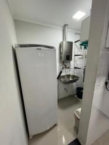 a small kitchen with a white refrigerator and a sink at Ohanacaiçara apartamento próximo à praia do Sesc, completo e com Wi-Fi. in Bertioga