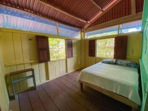 sypialnia z łóżkiem w pokoju z oknami w obiekcie Casa en la selva con acceso al río - Casa Ikua w mieście Iquitos