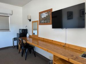 einen Schreibtisch mit einem großen TV an der Wand in der Unterkunft Eastern Sierra Motor Lodge in Independence