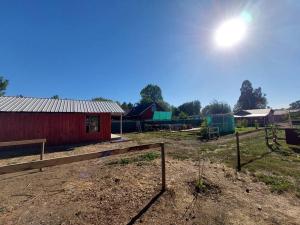 una granja con un granero rojo y una valla en Cabaña El Aromo, en Linares