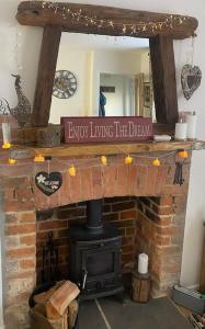 a brick fireplace with a sign that reads invent living the dream at Cosy cottage in Chard